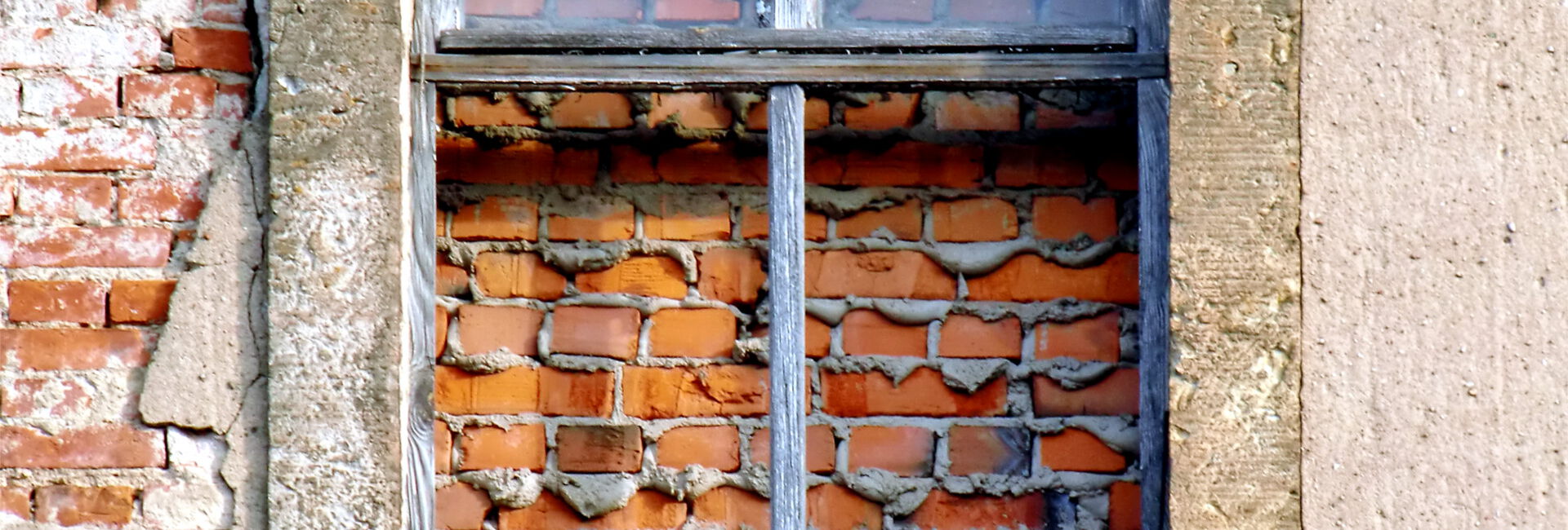Vermauertes Fenster in alter Backsteinwand.