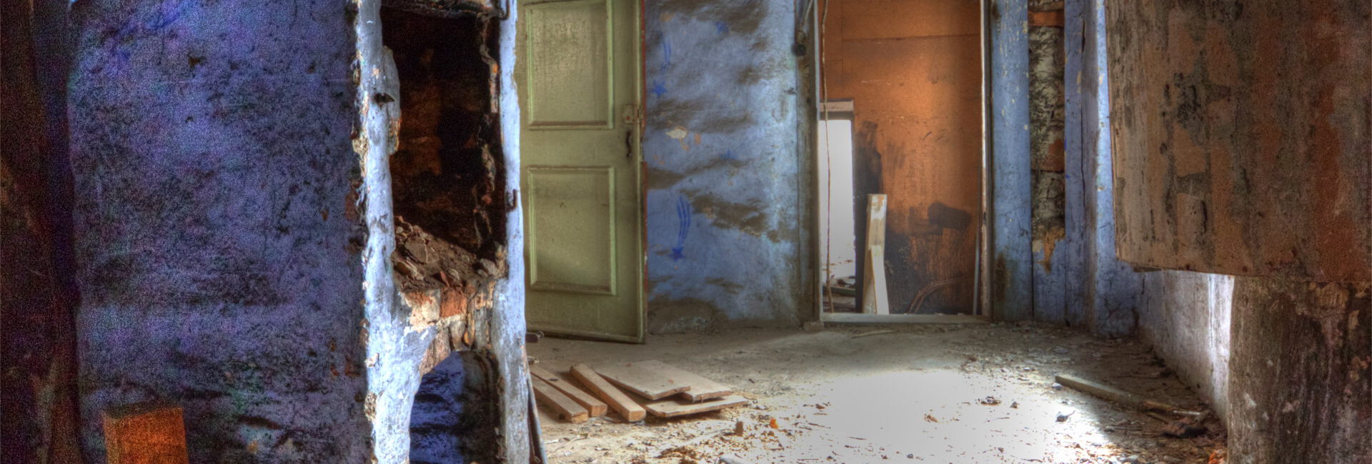 Verfallener Flur mit blauem Kamin und Schutt.